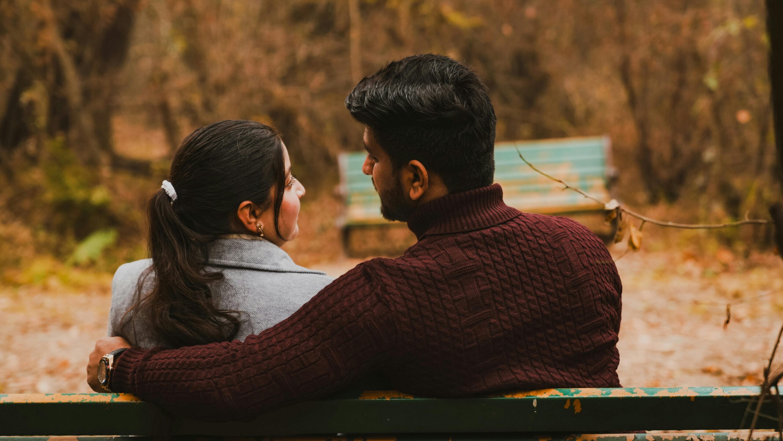 service-1 A couple sitting on a park bench, embracing in a romantic autumn setting.