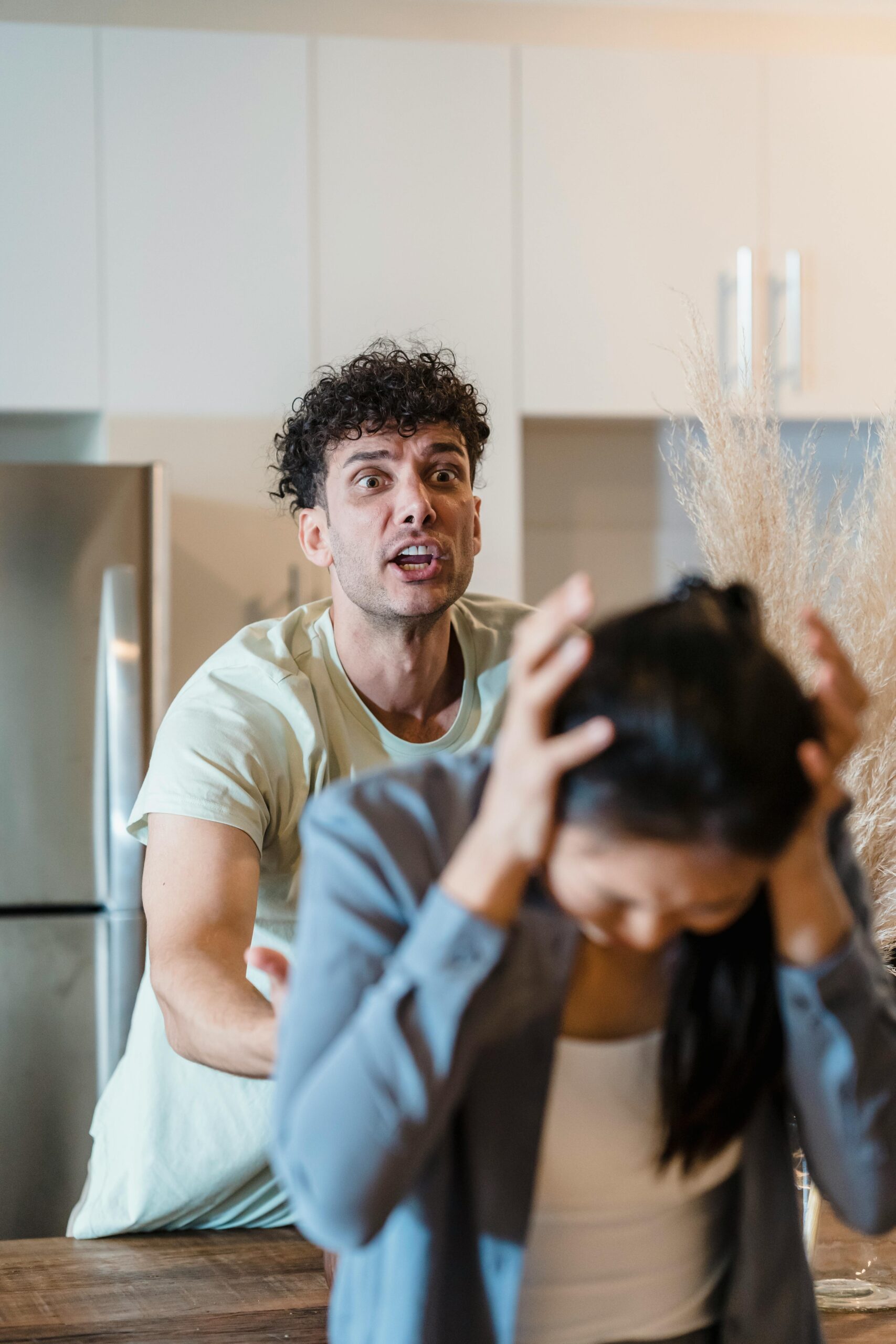 service-1 A man and woman in a tense emotional confrontation in a kitchen setting.